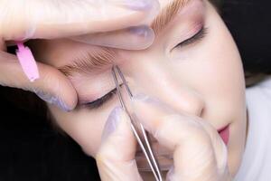 Korrektur und zupfen von Überschuss Haare nach das Augenbraue Laminierung Verfahren foto