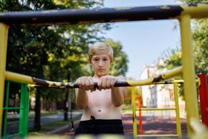 das Kind hält auf zu das Handläufe von das Sport horizontal Riegel. Straße trainieren auf ein horizontal Bar im das Schule Park. foto