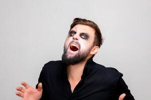 ein Mann mit ein Bart und bilden im das Stil von das Untote auf Halloween geöffnet seine Mund und zeigt an seine Zähne foto