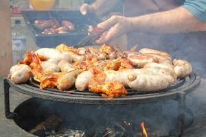 gebraten Würste und Hähnchen Flügel auf Grill Grill im das Dorf. braten Fleisch auf öffnen Feuer. Grill Party auf Hinterhof von Land Haus Kabine. Straße Essen Festival. Zuhause Kochen draussen. Picknick Zeit foto