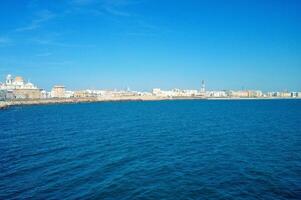 Cadiz Damm Panorama mit Kathedrale das Santa cruz, groß Wellenbrecher Steine und atlantisch Ozean. direkt am Meer Aussicht von Cádiz. Aussicht von das Promenade Kai Andalusien Region, Spanien foto