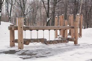 hölzern Spielplatz gemacht von natürlich umweltfreundlich Material im Öffentlichkeit Stadt Park mit Schnee beim Winter Zeit. modern Sicherheit Kinder draussen Ausrüstung. Winter Aktivitäten. Kinder sich ausruhen und Spiele auf öffnen Luft foto