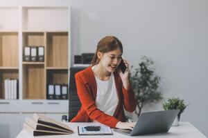 glücklich aufgeregt asiatisch Geschäft Frau im Büro Arbeiten mit Handy, Mobiltelefon Telefon, ja großartig Arbeit. foto