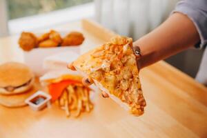 abgeschnitten Bild von Frau halten Pizza Scheibe beim Restaurant foto