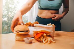 zu Essen oder nicht. freudlos rundlich Frau suchen beim das Burger während Denken zu Essen es oder nicht foto