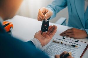 Versicherung Offiziere Hand Über das Auto Schlüssel nach das Mieter. haben unterzeichnet ein Auto Versicherung dokumentieren oder ein mieten oder Zustimmung dokumentieren Kauf oder Verkauf ein Neu oder benutzt Auto mit ein Auto foto