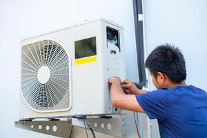 männlich Techniker Installation draussen Einheit von Luft Conditioner zu cool das Haushalt im das Sommer. Luft Kompressor, elektronisch, heiß Sommer, hoch Temperatur, tropisch Länder foto