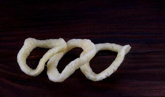 Zwiebel Ringe auf ein dunkel Hintergrund. Chips auf ein hölzern Tafel foto