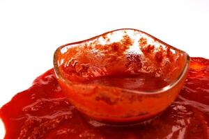 Tomate Soße . Glas Tasse mit verbleibend Ketchup und Ketchup verschüttet um Es. foto