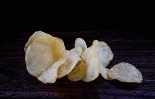 Kartoffel Chips auf ein dunkel Hintergrund. Chips auf ein hölzern Tafel foto