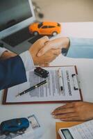 Versicherung Offiziere Hand Über das Auto Schlüssel nach das Mieter. haben unterzeichnet ein Auto Versicherung dokumentieren oder ein mieten oder Zustimmung dokumentieren Kauf oder Verkauf ein Neu oder benutzt Auto mit ein Auto foto
