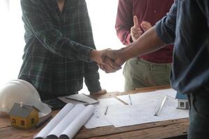 Ingenieur und Auftragnehmer beitreten Hände nach Unterzeichnung Vertrag, sie sind haben ein modern Gebäude Projekt zusammen. erfolgreich Zusammenarbeit Mannschaft Konzept foto