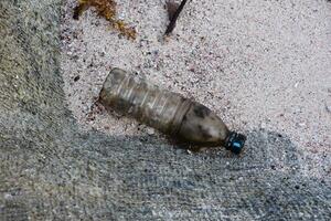 schmutzig Plastik Flasche auf ein Sand Strand foto