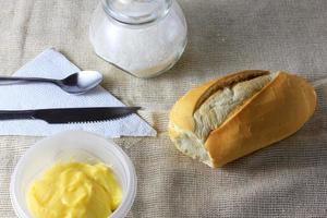 Nahaufnahme von französischem Brot auf hölzernem Frühstückstisch mit Butter und Besteck? foto