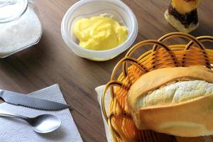 Nahaufnahme von französischem Brot auf hölzernem Frühstückstisch mit Butter und Besteck? foto