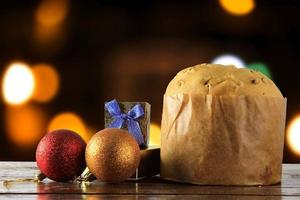 Panettone, dekoratives Essen, auf Holztisch, verschwommene Lichter im Hintergrund foto