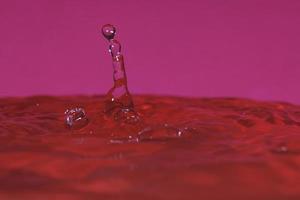 Spritzer durch den Aufprall eines Tropfens auf einen mit Wasser gefüllten Behälter foto