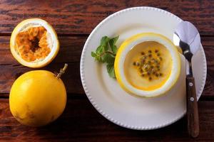 Dessert Passionsfruchtmousse in der Fruchtschale, auf Teller über rustikalem Holztisch foto