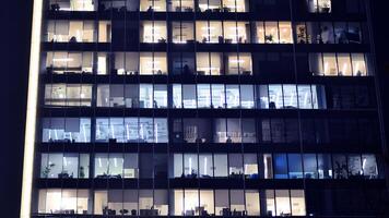 Fragment von das Glas Fassade von ein modern korporativ Gebäude beim Nacht. modern Glas Büro im Stadt. groß glühend Fenster im modern Büro Gebäude beim Nacht, im Reihen von Fenster Licht leuchtet. foto