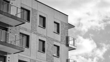 Fragment von das Gebäude Fassade mit Fenster und Balkone. modern Wohnung Gebäude auf ein sonnig Tag. Fassade von ein modern Wohn Gebäude. schwarz und Weiß. foto