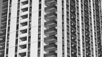 Fragment von das Gebäude Fassade mit Fenster und Balkone. modern Wohnung Gebäude auf ein sonnig Tag. Fassade von ein modern Wohn Gebäude. schwarz und Weiß. foto