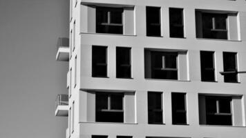 Fragment von das Gebäude Fassade mit Fenster und Balkone. modern Wohnung Gebäude auf ein sonnig Tag. Fassade von ein modern Wohn Gebäude. schwarz und Weiß. foto