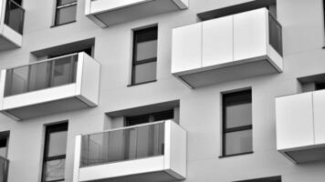 Fragment von das Gebäude Fassade mit Fenster und Balkone. modern Wohnung Gebäude auf ein sonnig Tag. Fassade von ein modern Wohn Gebäude. schwarz und Weiß. foto