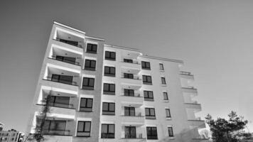 Fragment von das Gebäude Fassade mit Fenster und Balkone. modern Wohnung Gebäude auf ein sonnig Tag. Fassade von ein modern Wohn Gebäude. schwarz und Weiß. foto