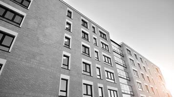 Fragment von das Gebäude Fassade mit Fenster und Balkone. modern Wohnung Gebäude auf ein sonnig Tag. Fassade von ein modern Wohn Gebäude. schwarz und Weiß. foto