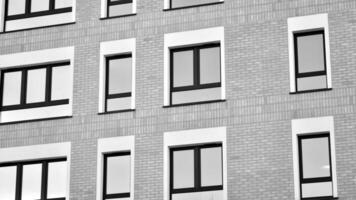 Fragment von das Gebäude Fassade mit Fenster und Balkone. modern Wohnung Gebäude auf ein sonnig Tag. Fassade von ein modern Wohn Gebäude. schwarz und Weiß. foto