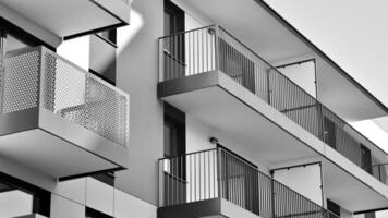 Fragment von das Gebäude Fassade mit Fenster und Balkone. modern Wohnung Gebäude auf ein sonnig Tag. Fassade von ein modern Wohn Gebäude. schwarz und Weiß. foto