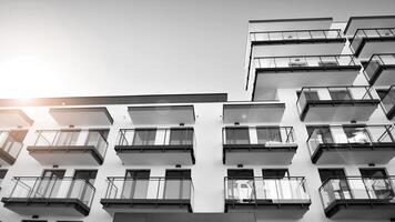 Fragment von ein Fassade von ein Gebäude mit Fenster und Balkone. modern Wohnung Gebäude auf ein sonnig Tag. Fassade von ein modern Wohnung Gebäude. schwarz und Weiß. foto