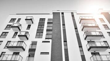 Fragment von ein Fassade von ein Gebäude mit Fenster und Balkone. modern Wohnung Gebäude auf ein sonnig Tag. Fassade von ein modern Wohnung Gebäude. schwarz und Weiß. foto