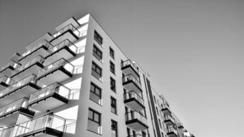 Fragment von ein Fassade von ein Gebäude mit Fenster und Balkone. modern Wohnung Gebäude auf ein sonnig Tag. Fassade von ein modern Wohnung Gebäude. schwarz und Weiß. foto