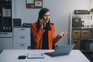 Geschäftsfrau Lächeln habe gut Nachrichten auf Smartphone während Arbeiten auf Computer foto