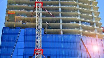 hoch erhebt euch Gebäude unter Konstruktion. Installation von Glas Fassade Paneele auf ein verstärkt Beton Struktur. foto