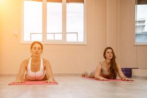 zwei schön Frauen tun Yoga, Sport im das Fitnessstudio. das Konzept von Anmut und Schönheit von das Körper. foto