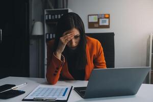 Porträt von müde jung Geschäft asiatisch Frau Arbeit mit Unterlagen MwSt Laptop Computer im Büro. traurig, unzufrieden, besorgt, Depression, oder Mitarbeiter Leben Stress Konzept foto