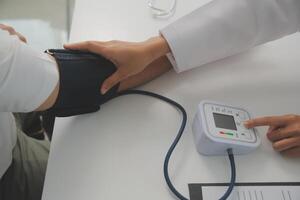 männlich Arzt Verwendet ein Blut Druck Monitor zu prüfen das Körper Druck und Impuls von das Patienten Wer Kommen Sie zu das Krankenhaus zum Kontrolluntersuchungen, medizinisch Behandlung und Gesundheit Pflege Konzept. foto