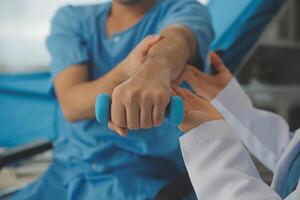 Physiotherapeut Mann geben Übung mit Hantel Behandlung Über Arm und Schulter von Athlet männlich geduldig physisch Therapie Konzept foto