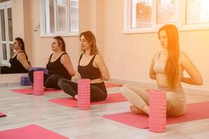 ein Gruppe von sechs sportlich Frauen tun Pilates oder Yoga auf Rosa Matten im Vorderseite von ein Fenster im ein Beige Dachgeschoss Studio Innere. Zusammenarbeit, gut Stimmung und gesund Lebensstil Konzept. foto