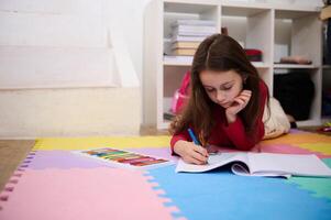 Clever klein Schülerin studieren beim heim, Handschrift im Notizbuch. hart arbeitend konzentriert wenig Mädchen Kind Zeichnung Bild, tun Hausaufgaben Lektionen allein, Gefühl motiviert beim Lernen, Bildung Konzept foto