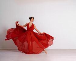 Tänzer im ein rot fliegend Kleid. Frau Ballerina Tanzen auf ein Weiß Studio Hintergrund foto