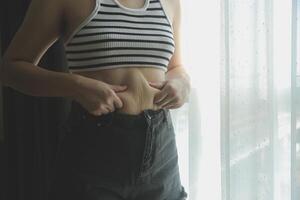 Frauen Körper Fett Bauch. fettleibig Frau Hand halten übermäßig Bauch fett. Diät Lebensstil Konzept zu reduzieren Bauch und gestalten oben gesund Bauch Muskel. foto