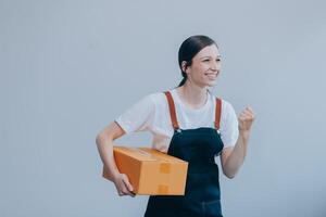 lächelnd asiatisch Frau im beiläufig Kleider halten ein Karton Box Attrappe, Lehrmodell, Simulation während Stehen gegen ein isoliert Weiß Hintergrund. Versand Geschäft Konzept foto