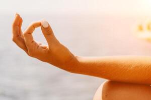 Yoga auf das Strand. ein glücklich Frau meditieren im ein Yoga Pose auf das Strand, umgeben durch das Ozean und Felsen Berge, fördern ein gesund Lebensstil draußen im Natur, und inspirierend Fitness Konzept. foto