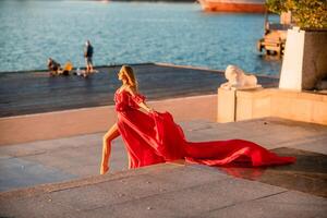 Sonnenaufgang rot Kleid. ein Frau im ein lange rot Kleid gegen das Hintergrund von Sonnenaufgang, hell golden Licht von das Sonne Strahlen. das Konzept von Weiblichkeit, Harmonie. foto