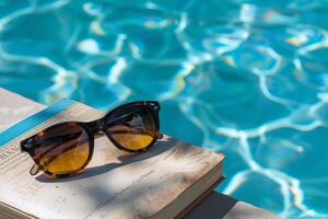 Paar von Sonnenbrille ruhen auf Buch durch das am Pool, Inbegriff faul Sommer- Tage foto