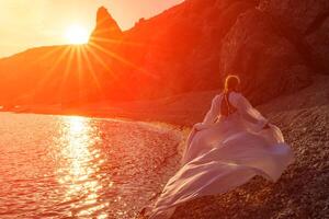 mysteriös Frau Silhouette lange Haar Spaziergänge auf das Strand Ozean Wasser, Meer Nymphe Wind hört zu zu das Welle. wirft oben ein lange Weiß Kleid, ein göttlich Sonnenuntergang. künstlerisch Foto von das zurück ohne ein Gesicht