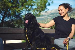 schön Frau Sitzung auf Stadt Bank mit ihr Hund während gehen im das Morgen foto